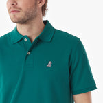 Close-up of a man wearing a green polo shirt with a small logo on a white background