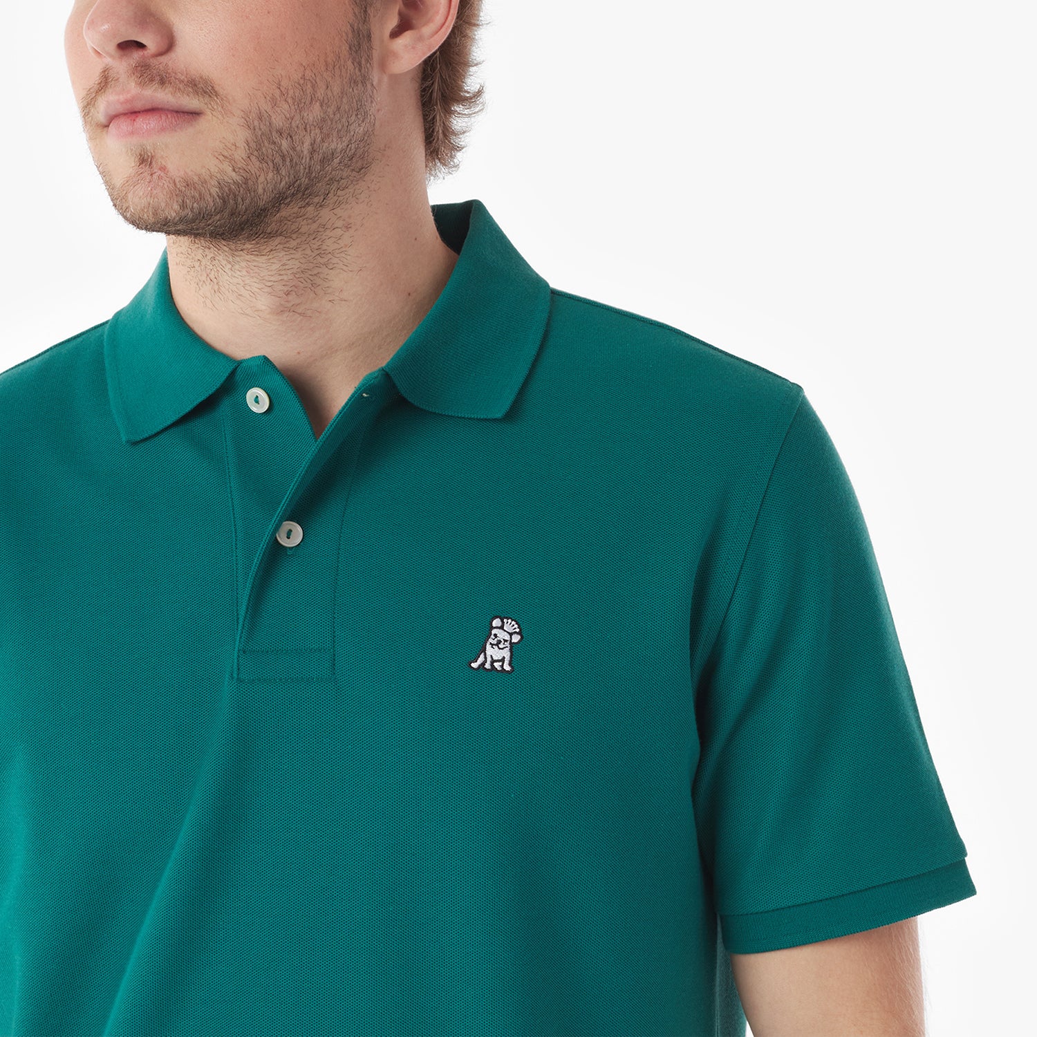 Close-up of a man wearing a green polo shirt with a small logo on a white background