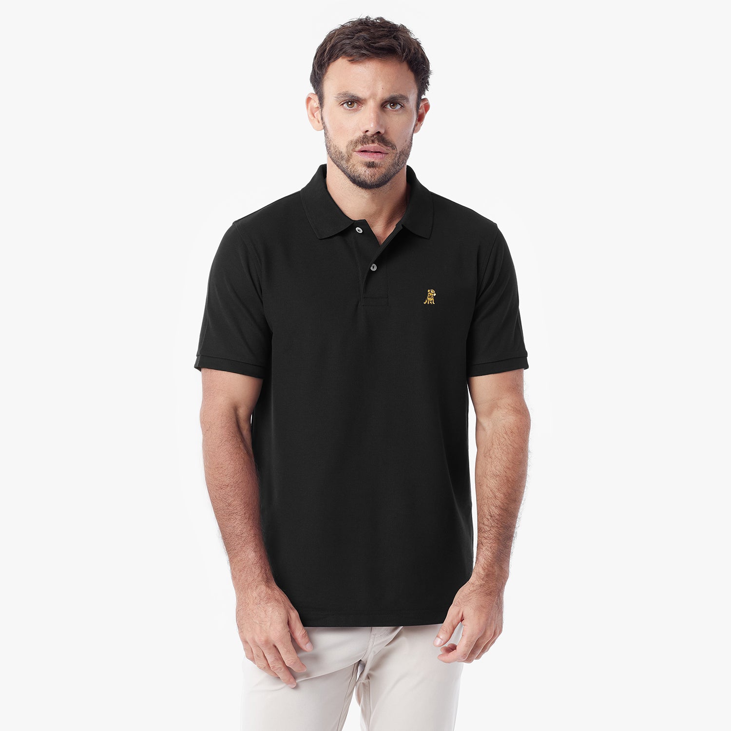 A man wearing a black short-sleeve polo shirt with a small gold embroidered logo on the left chest