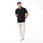 A man modeling a black short-sleeve polo shirt with a small embroidered logo on the chest, paired with light beige trousers