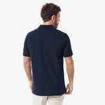 A man viewed from the back wearing a navy blue short-sleeve polo shirt and light beige trousers