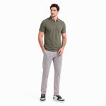 Man wearing a green polo shirt and gray pants on a white background