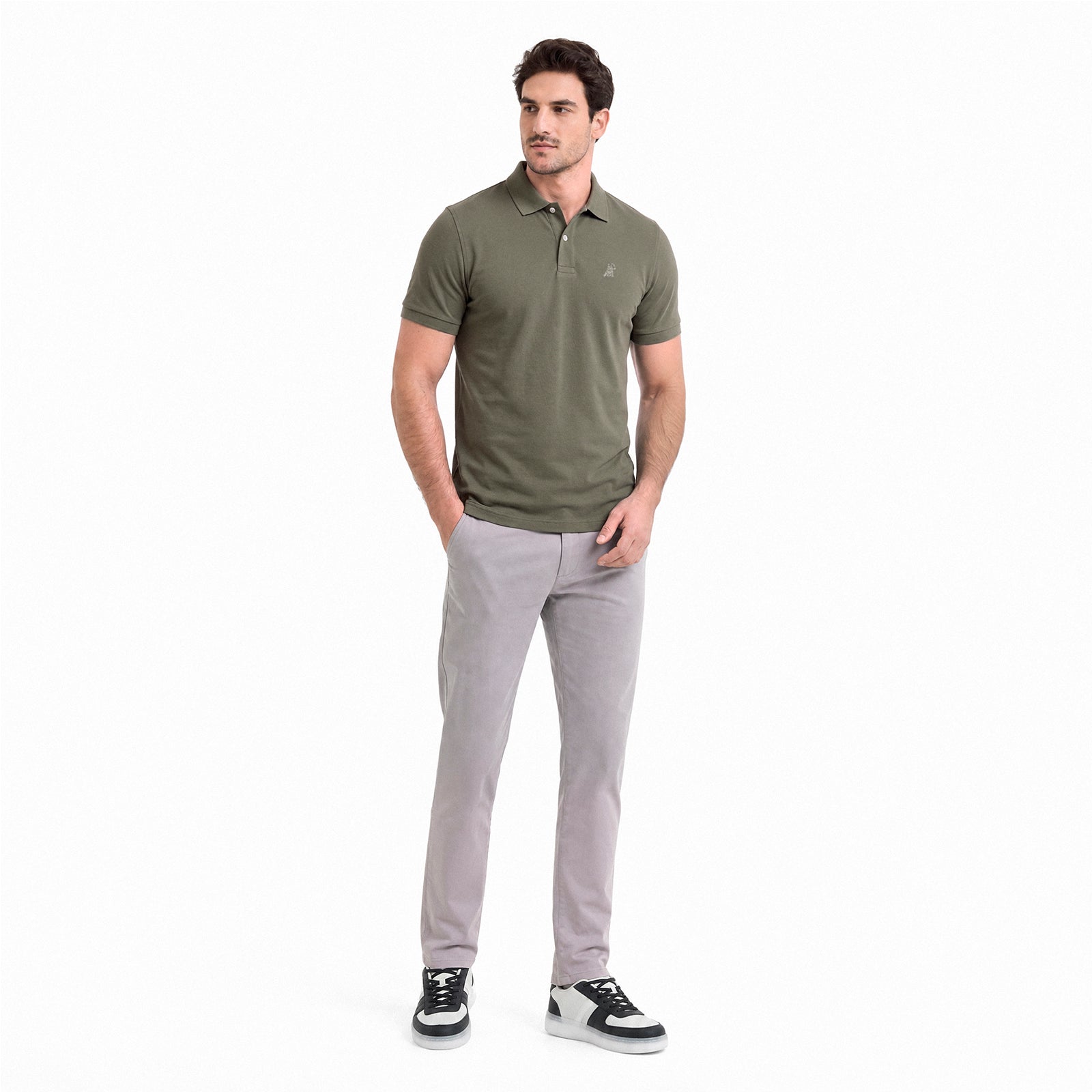 Man wearing a green polo shirt and gray pants on a white background