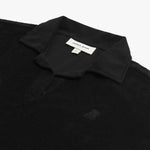 Detail view of a black collared shirt's neckline and embroidered logo near the chest area