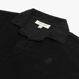 Detail view of a black collared shirt's neckline and embroidered logo near the chest area