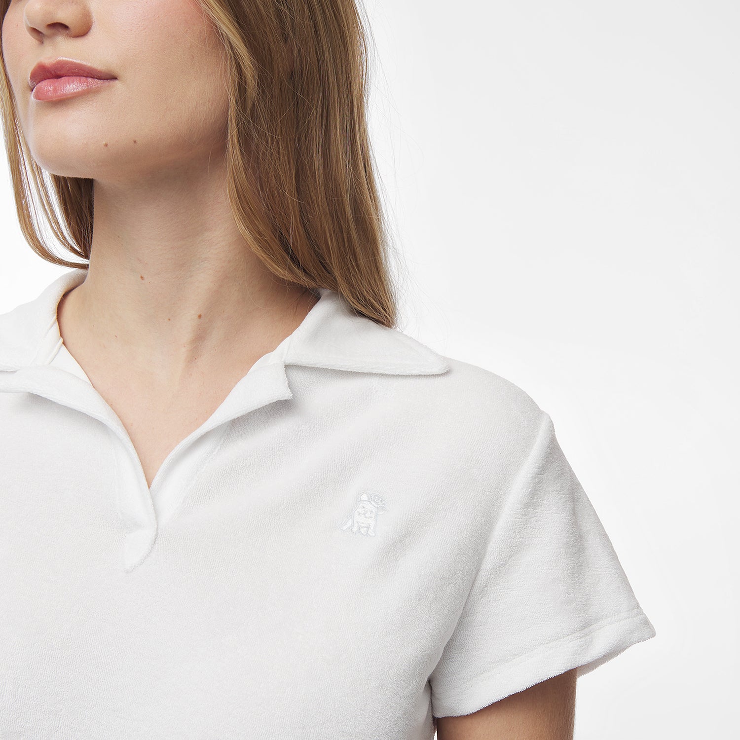 Side-close-up of a woman wearing a white collared shirt, focusing on the shirt’s collar and texture