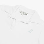 Detail view of the white collared shirt's neckline and embroidered logo near the chest area