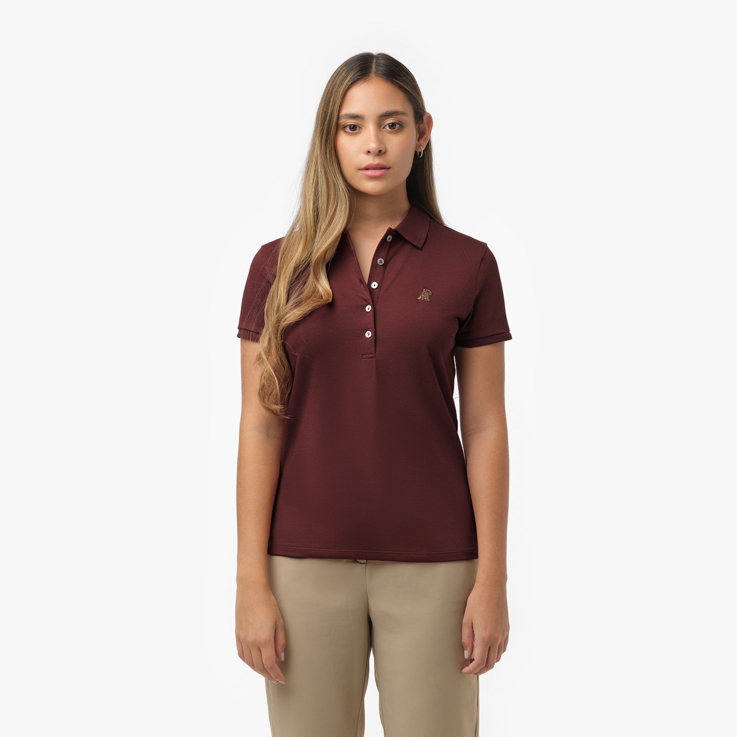 Woman models a maroon short-sleeve polo shirt with white buttons and small embroidered logo, paired with beige trousers. Front view against white background