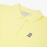 Close-up of the woman's chest area, highlighting the embroidered logo and button collar of the yellow polo shirt.