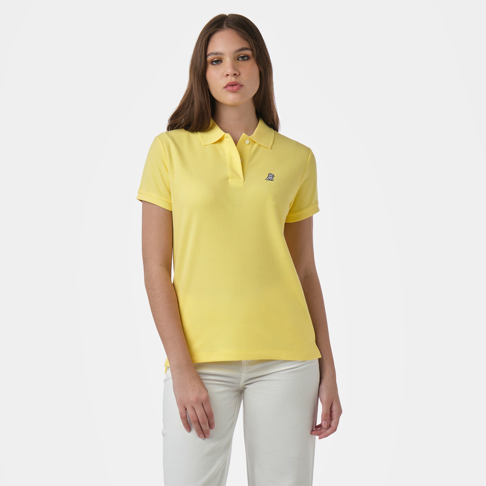 Front view of a woman wearing a yellow polo shirt with an embroidered logo on the chest, paired with white pants.