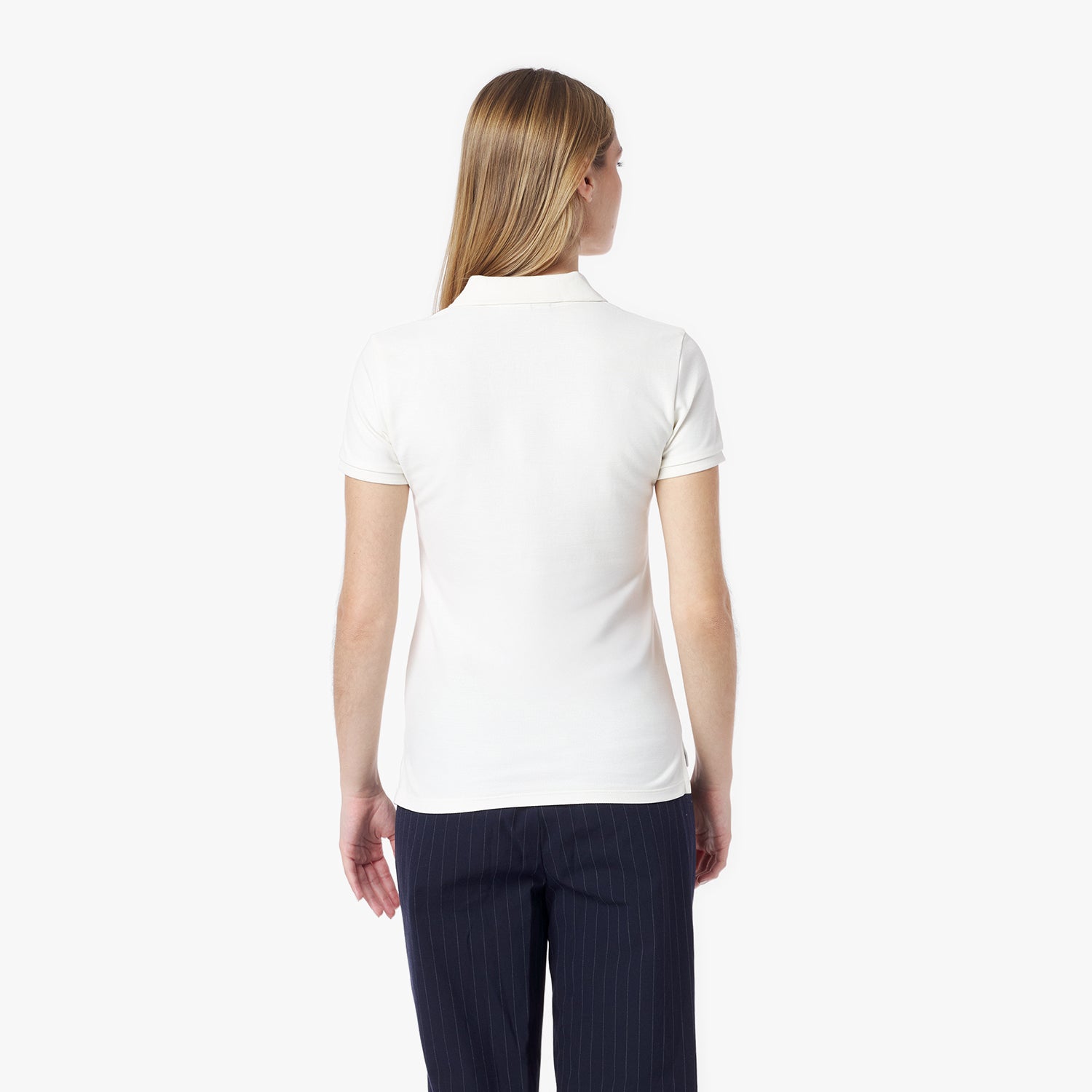 Back of a woman wearing a white polo shirt and dark pants on a white background