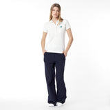 Full body picture of a woman wearing a white polo shirt and navy pants on a white background