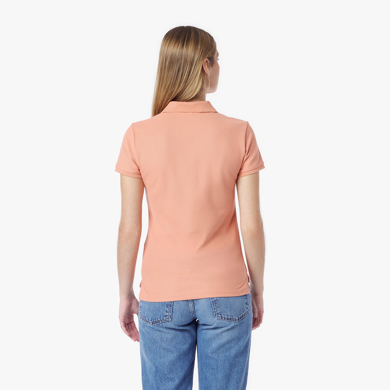 Back picture of a woman wearing a peach polo shirt and blue jeans on a white background