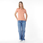 Woman wearing a peach polo shirt and blue jeans on a white background