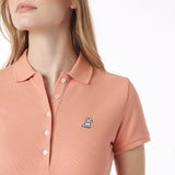 Close-up of a person wearing a pink polo shirt with a small logo on a white background