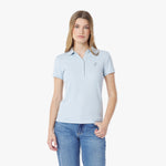 Woman wearing a light blue polo shirt and jeans on a white background