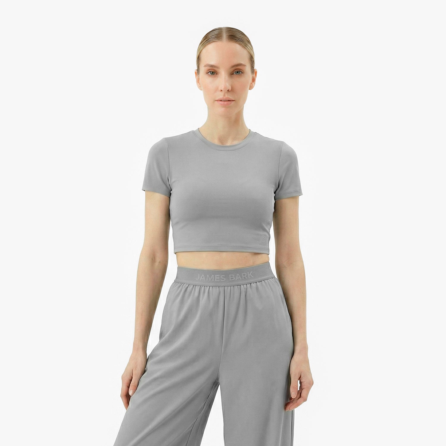 Woman wearing a gray athletic outfit with 'James Bark' branding on a white background