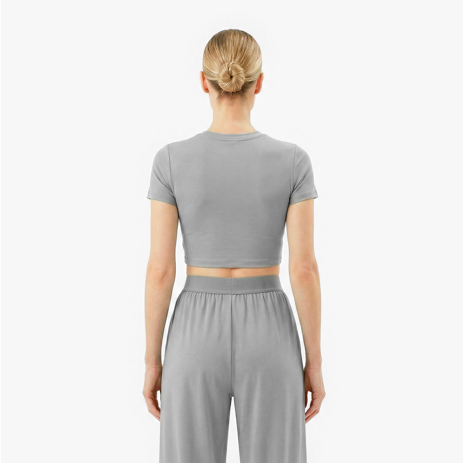 Person wearing a gray crop top and pants on a white background