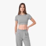 Woman wearing a gray crop top and pants on a white background