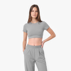 Woman wearing a gray crop top and pants on a white background