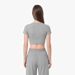 Woman wearing a gray crop top and pants on a white background