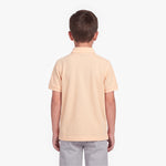 A child viewed from the back wearing a polo shirt in a pale peach-beige color