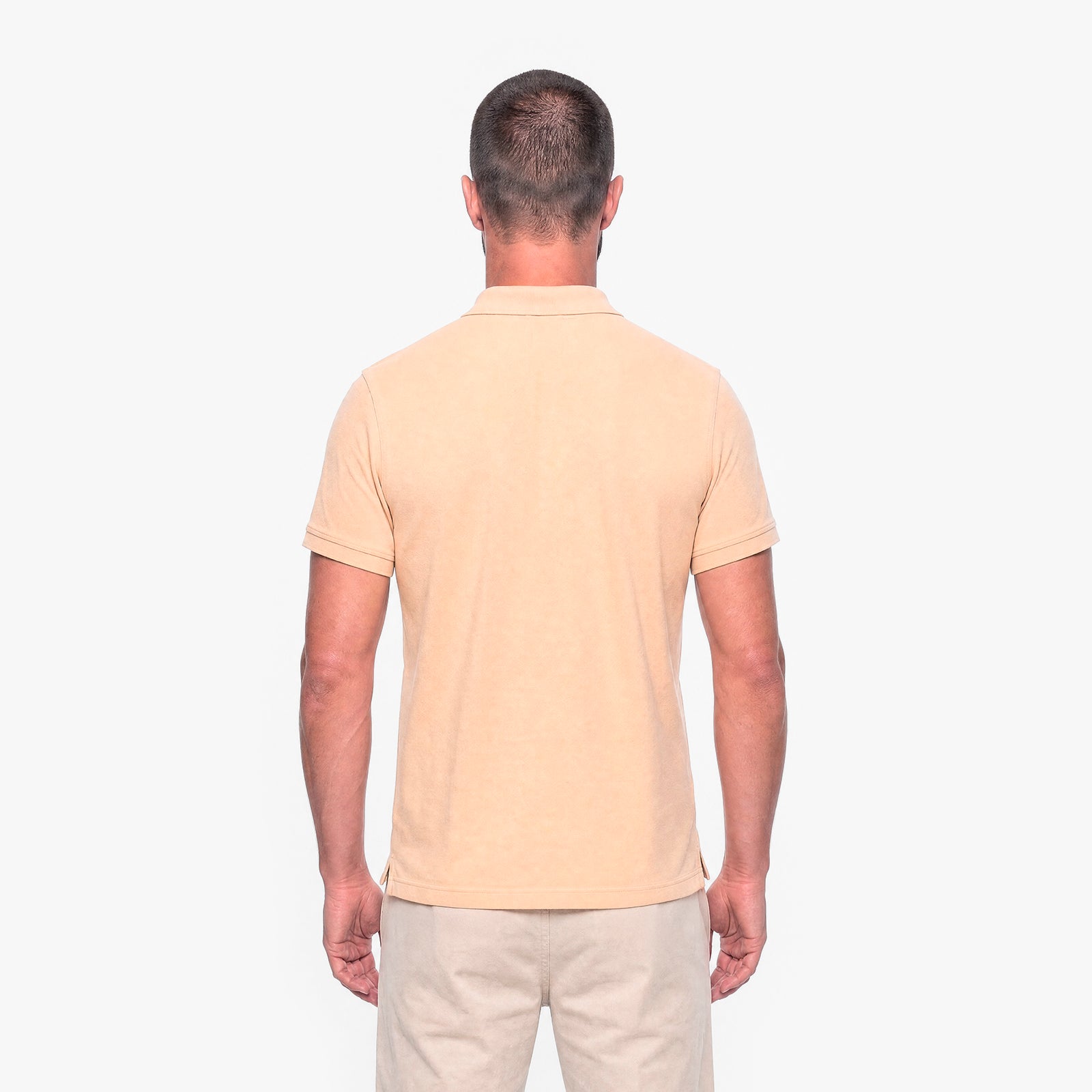 Man wearing a beige polo shirt and pants on a white background
