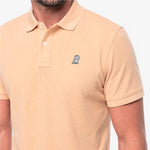 Close-up of a beige polo with a white embroidered logo 