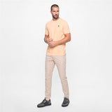 Man wearing a light peach t-shirt and beige pants on a white background