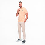 Man wearing a beige polo shirt and light-colored pants on a white background