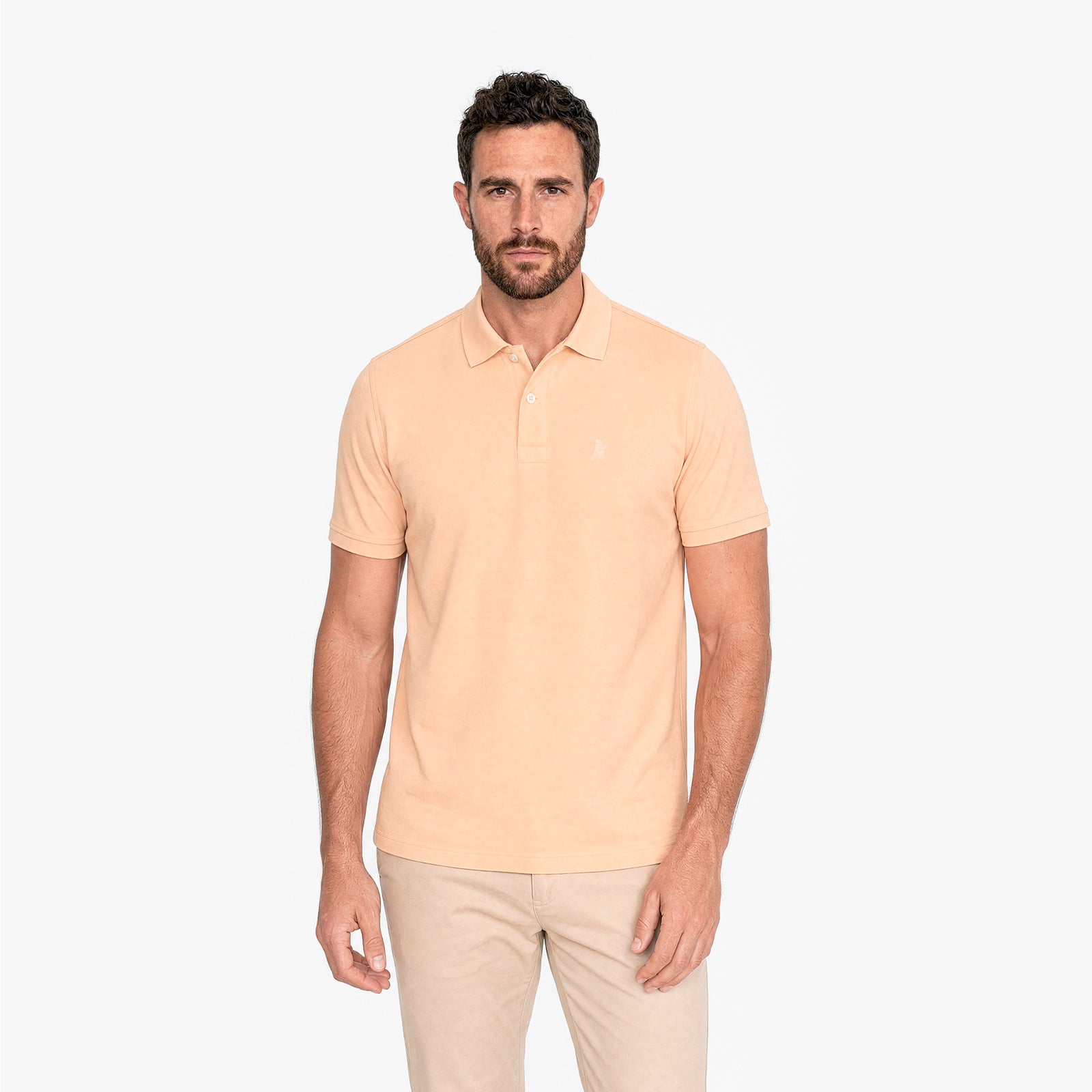Man wearing a light yellow polo shirt and beige pants on a white background