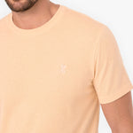Beige t-shirt with a small logo on a plain background