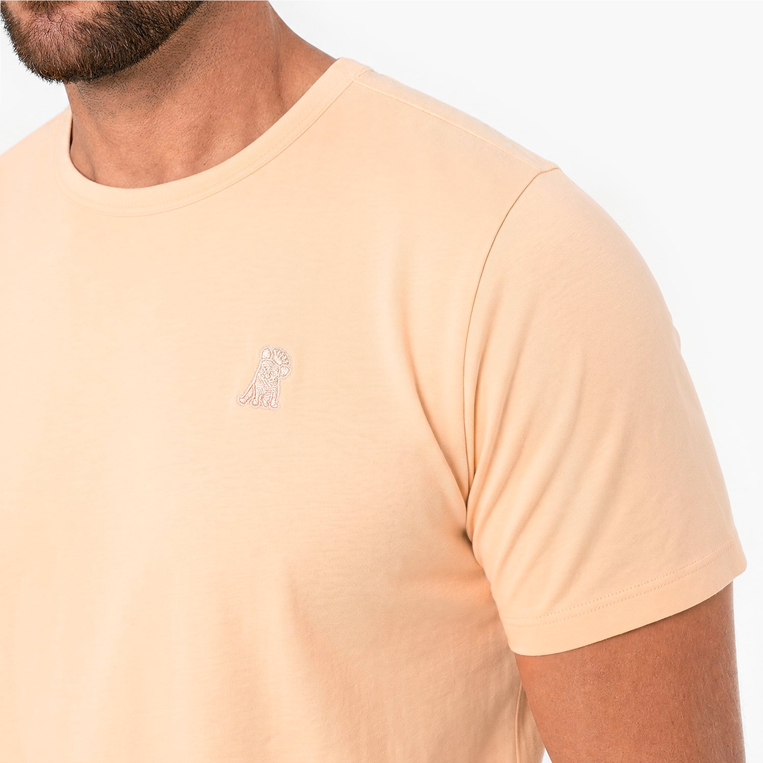 Close-up of a peach T-Shirt with a peach embroidered logo