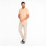 Man wearing a light beige polo shirt and pants on a white background