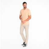 Man wearing a light beige polo shirt and pants on a white background