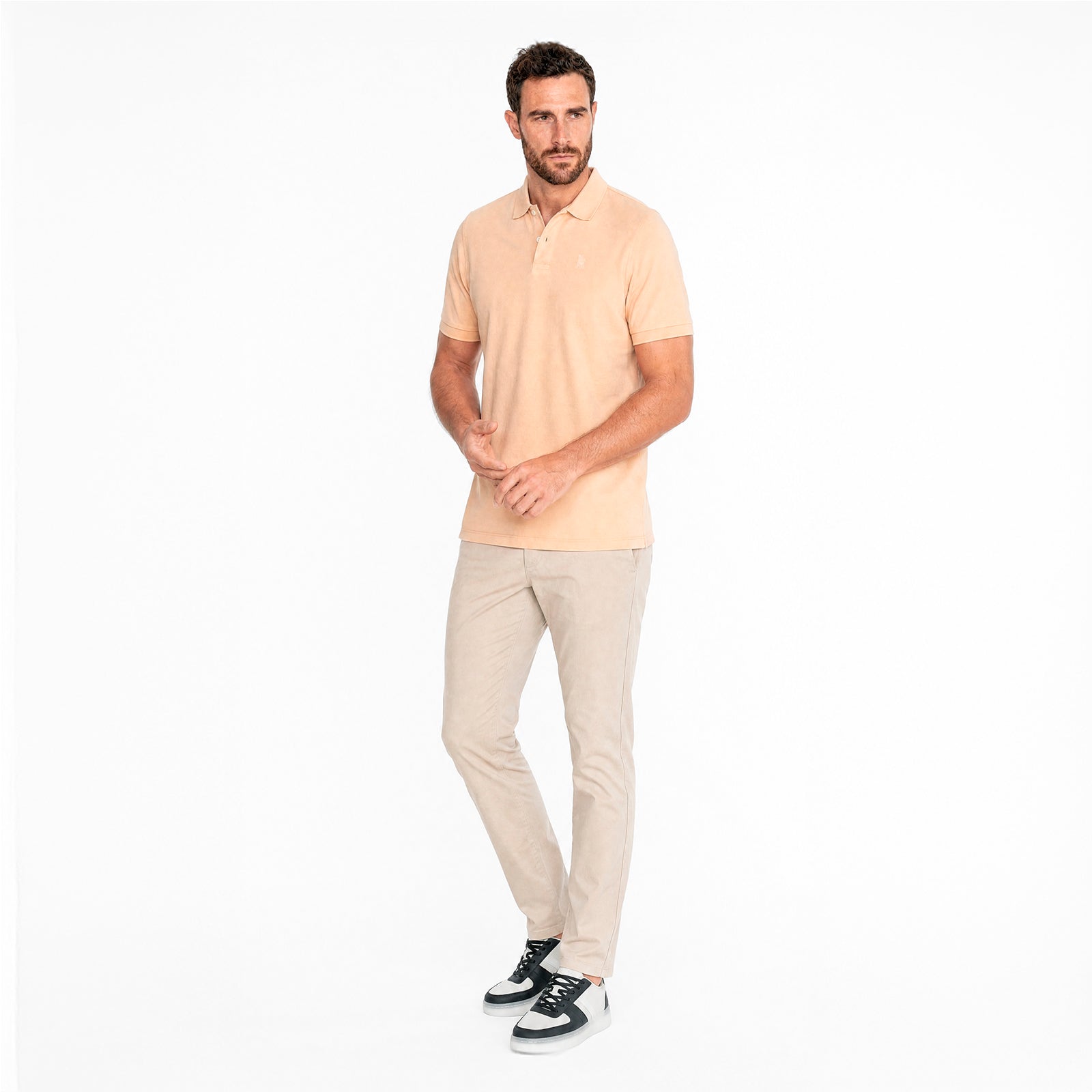 Man wearing a light beige polo shirt and pants on a white background