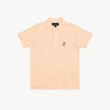 A light peach-pink polo shirt for kids, featuring a small navy embroidered dog logo on the left chest, set against a plain white background.