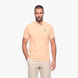 Man wearing a beige polo shirt with a small logo on a white background