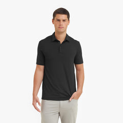 Man wearing a black polo shirt and light gray pants on a white background