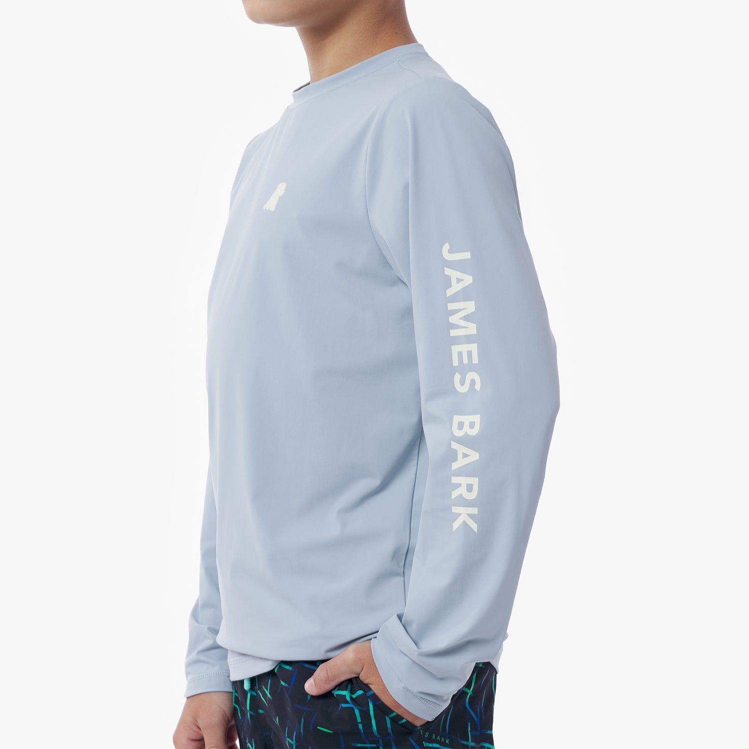 Side picture of the light blue long-sleeve rashguard with 'James Bark' branding on a white background