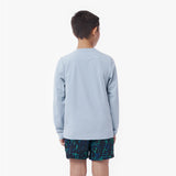 Back picture of a child wearing a light blue long-sleeve rashguard and dark shorts with a pattern on a white background