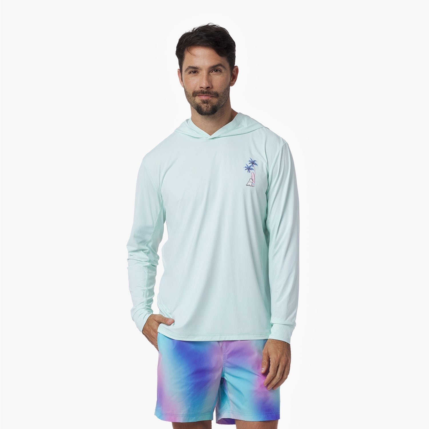 Man wearing a light blue rashguard and tie-dye shorts on a white background