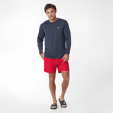 Man wearing a navy long-sleeve rashguard and red shorts on a white background