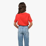 Rear view of the girl wearing the red T-shirt, showing the plain back design, paired with blue jeans.