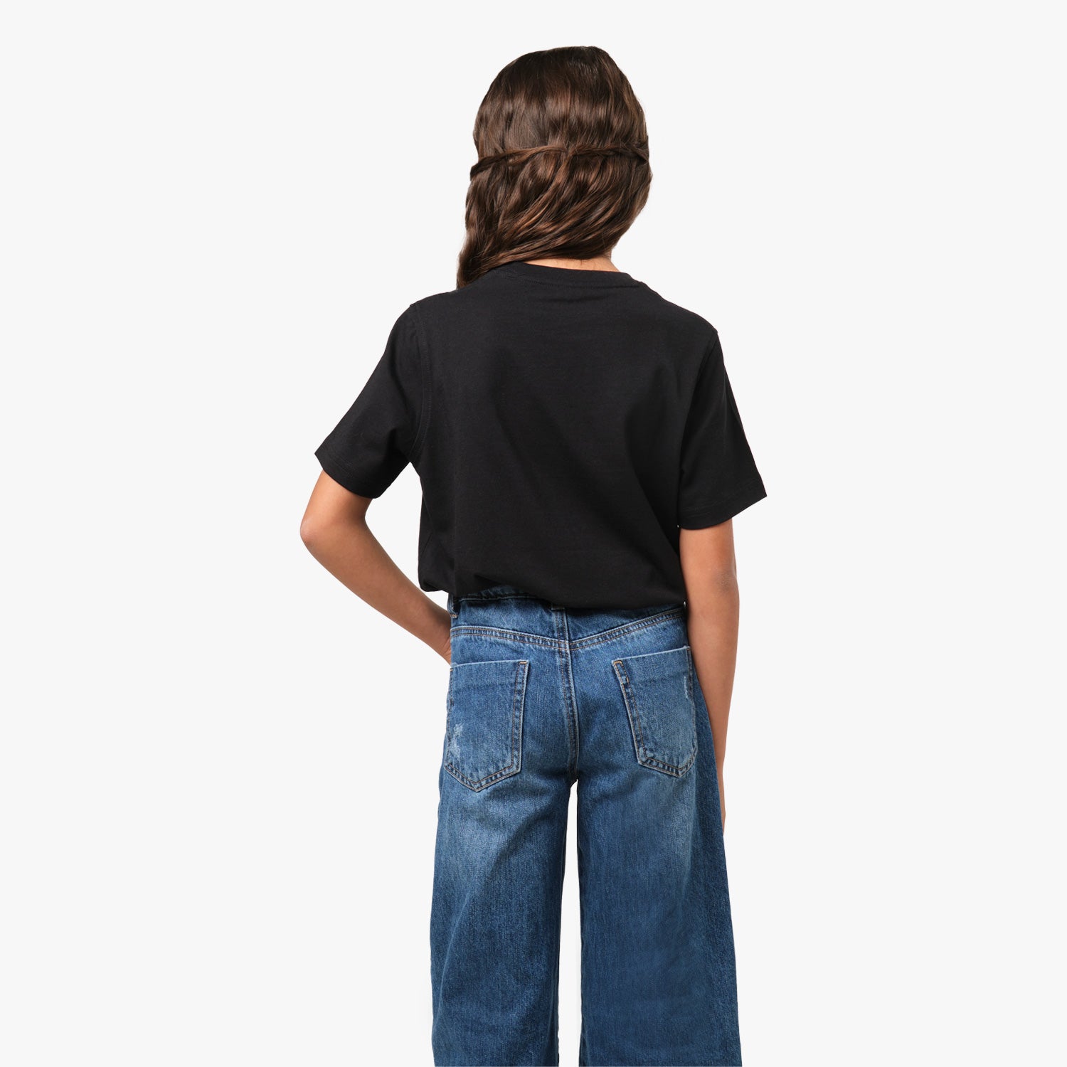 Rear view of the girl wearing the black T-shirt, showing the plain back design, paired with blue jeans.