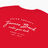 A close-up view of the back of a red T-shirt, highlighting the white printed text that reads 'PRIVÉ SOCIETY' at the top, followed by 'James Bark' in a script font, 'make your bark' underneath, and 'BASED IN USA EST. 2015' at the bottom