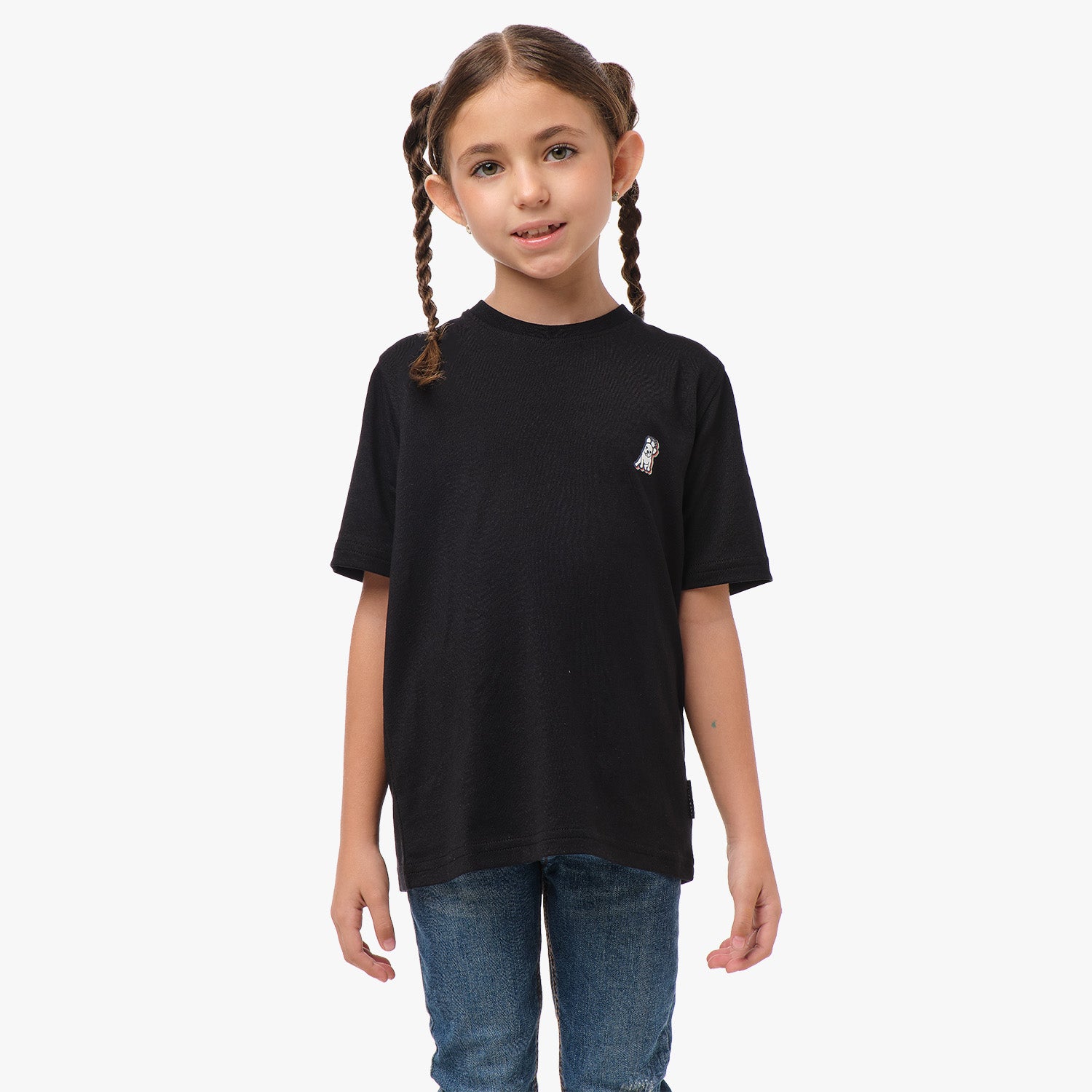 Front view of a young girl wearing a black T-shirt with a small dog graphic on the chest, paired with blue jeans.