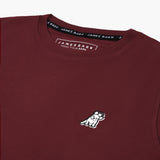 Close-up of the small embroidered logo on the front of the maroon t-shirt.