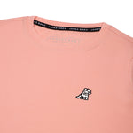 Close-up of the small white embroidered logo on the front of the light pink t-shirt.