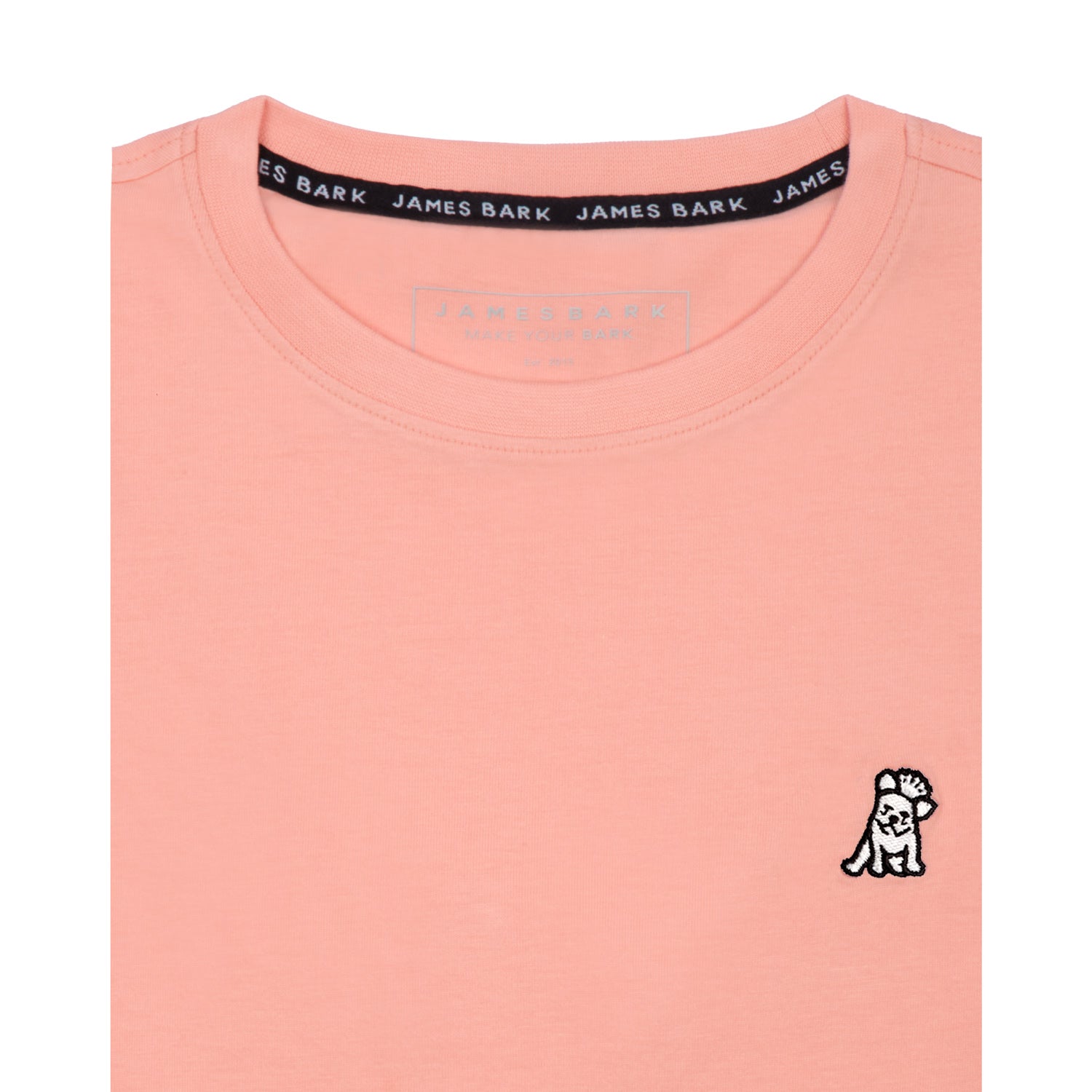 Close-up of the collar area of the light pink t-shirt, showing the small white embroidered logo on the chest.